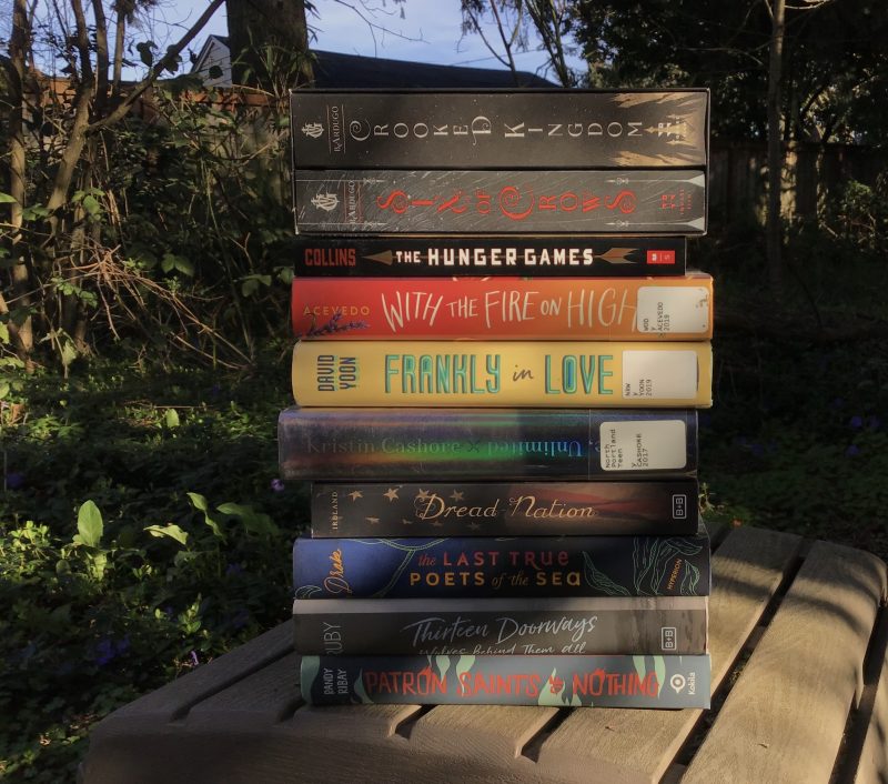 Stack of young adult novels in a leafy backyard