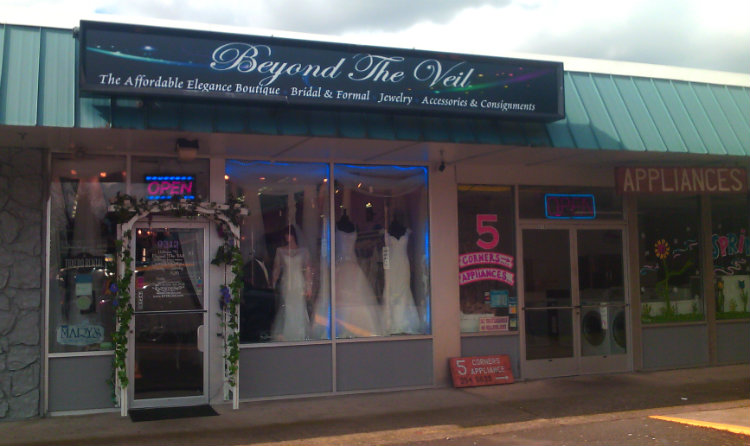 strip mall storefront: Beyond the Veil bridal shop with arch at doorway and mannequins in window