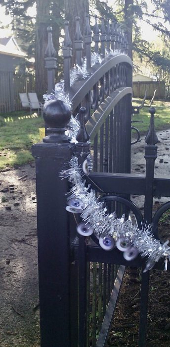 iron fence with garland made of tinsel and photos of eyeballs