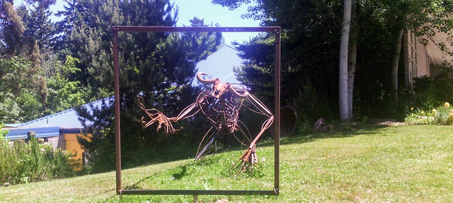 sculpture of monster reaching through a metal square frame