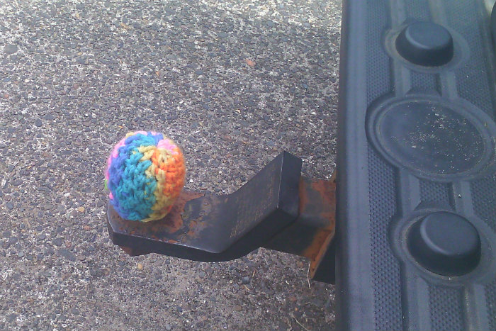 a trailer hitch with a knitted cozy in rainbow colors