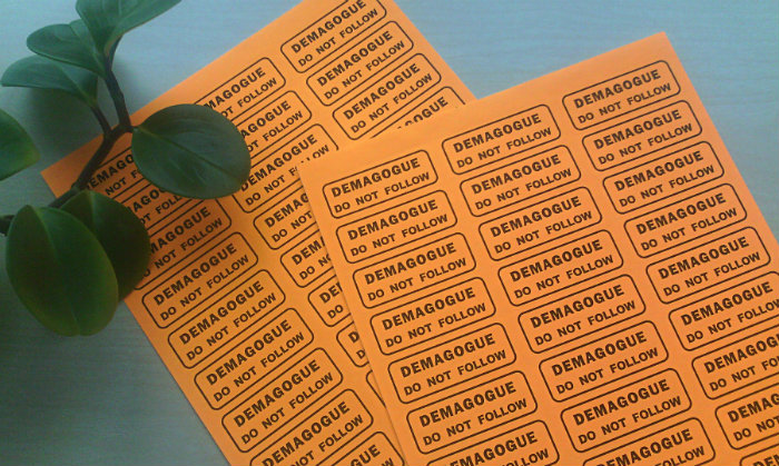 two sheets of orange mailing labels that read "DEMAGOGUE / DO NOT FOLLOW"