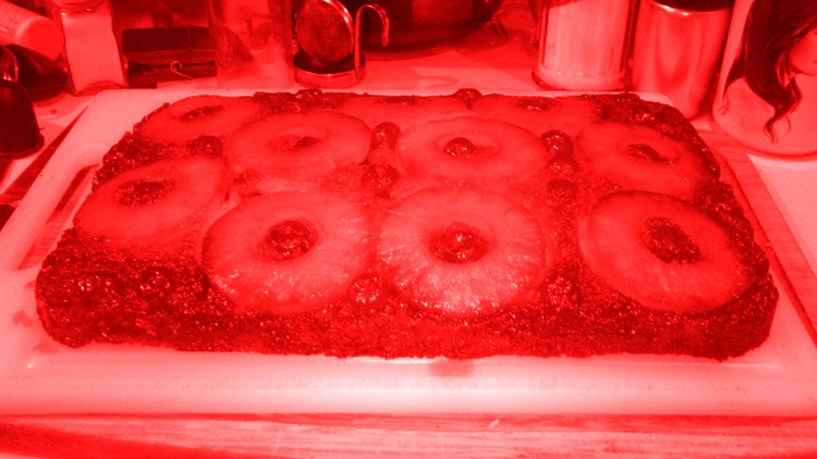 a homemade pineapple upside down cake; photo has a red filter